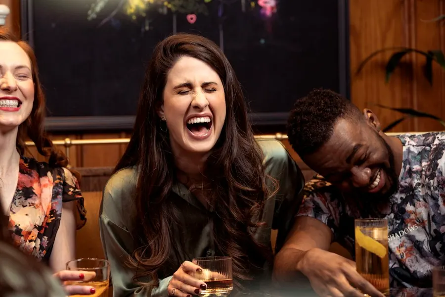 Two friends laughing out loud together at dinner.